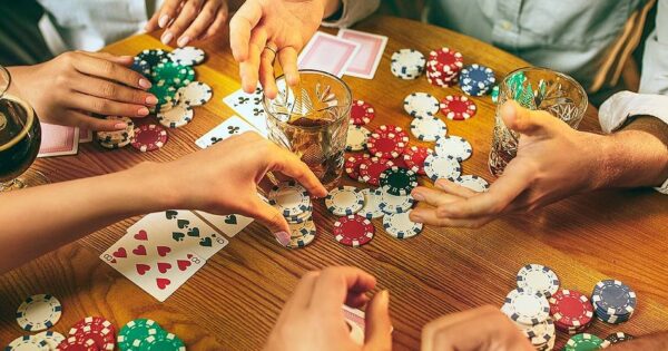 How to win at poker: Friends at the table playing poker Poker chips and cards lie on the table.