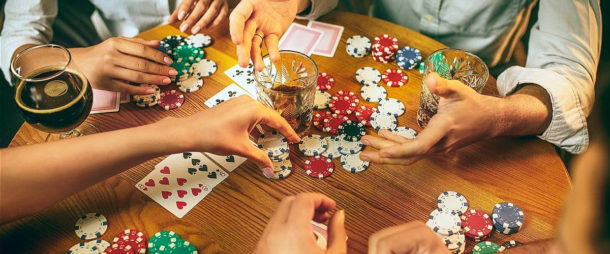 How to win at poker: Friends at the table playing poker Poker chips and cards lie on the table.