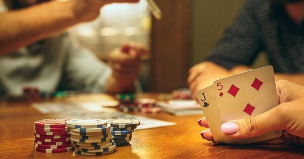 Learn poker: Player at a table with cards in hand and poker chip on the table