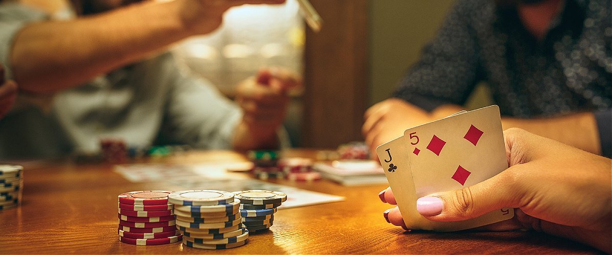 Learn poker: Player at a table with cards in hand and poker chip on the table