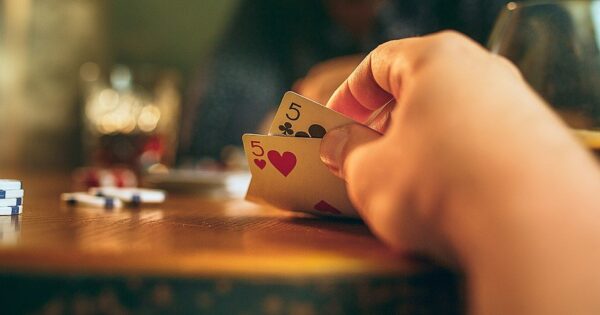 Texas Hold'em Poker, player at a table with cards in hand and poker chip on the table.