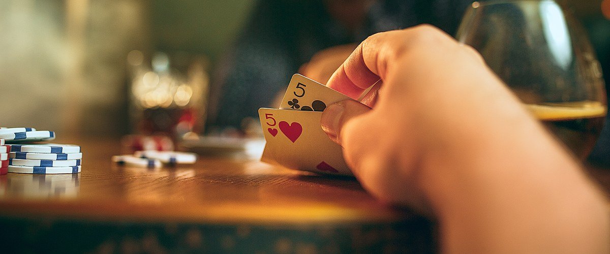 Texas Hold'em Poker, player at a table with cards in hand and poker chip on the table.